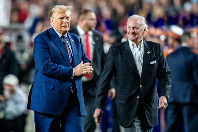 Donald Trump, left, and Henry McMaster walk next to each other on a football field